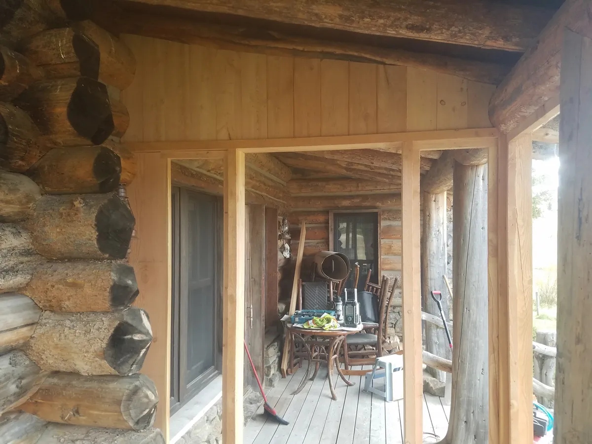 Timber frame covered porch interior showing beam connections and windows